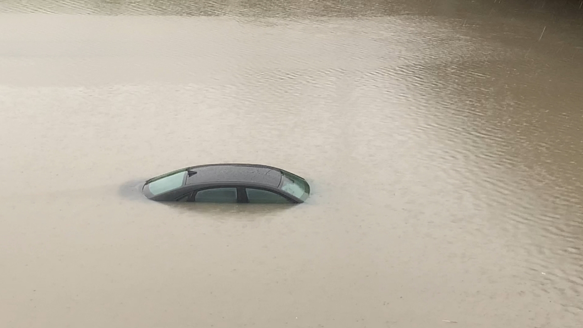 The car appears to be almost completely submerged on the highway.