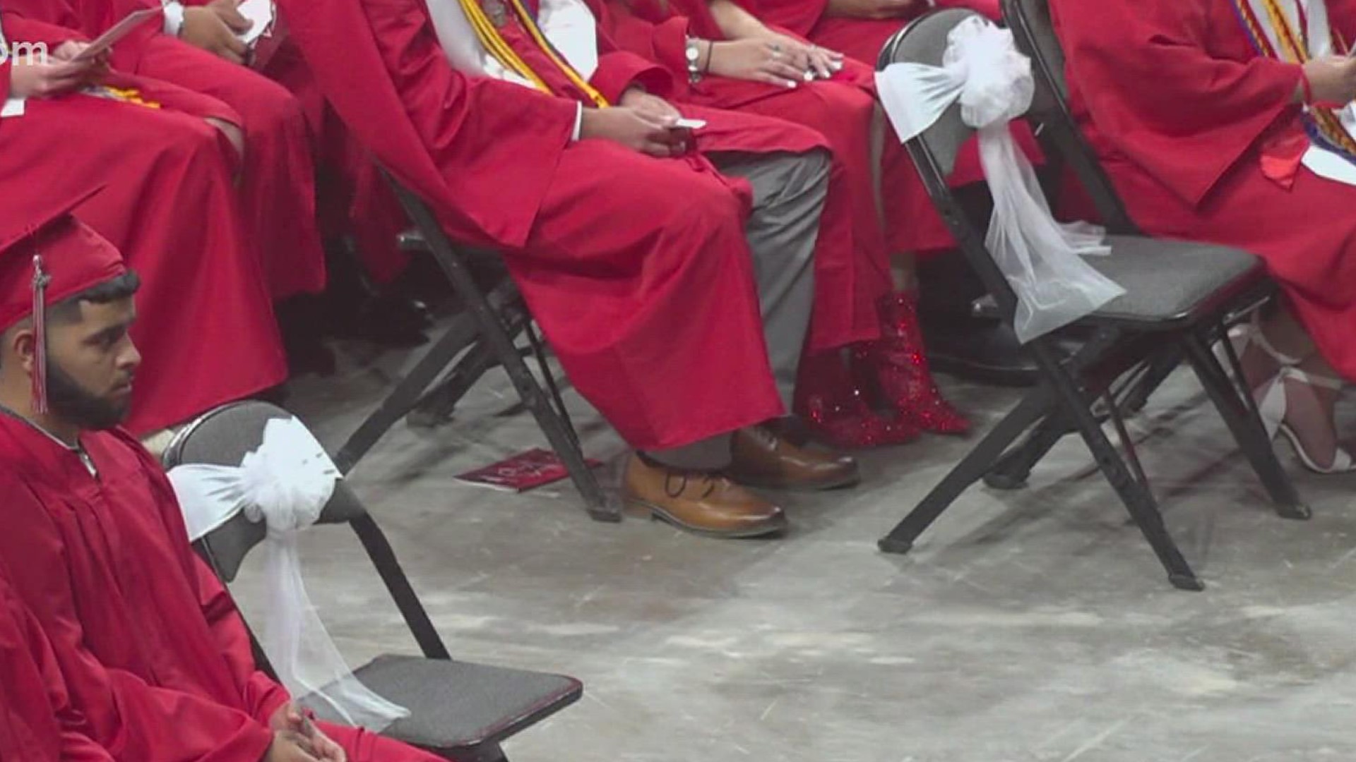 Among the sea of red cap and gowns, there were two chairs front and center that remained empty. Each one wrapped in a white bow.